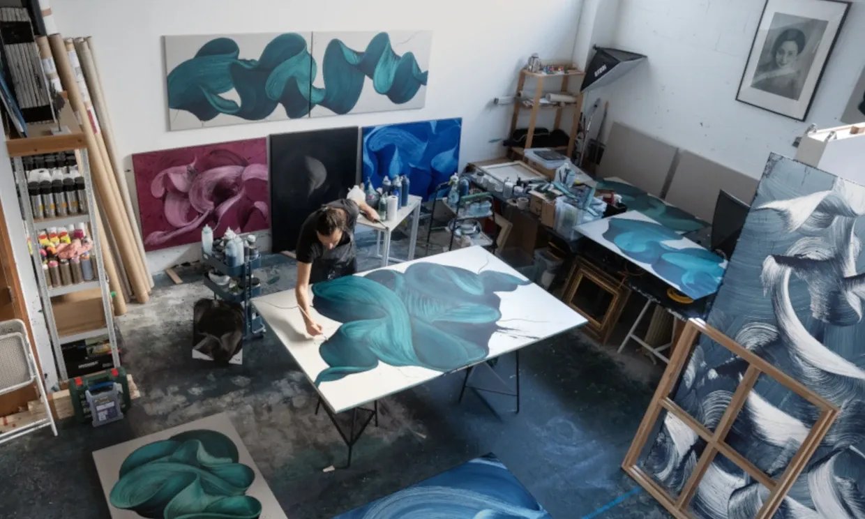 Kostas Papakostas painting in his studio surrounded by artworks.