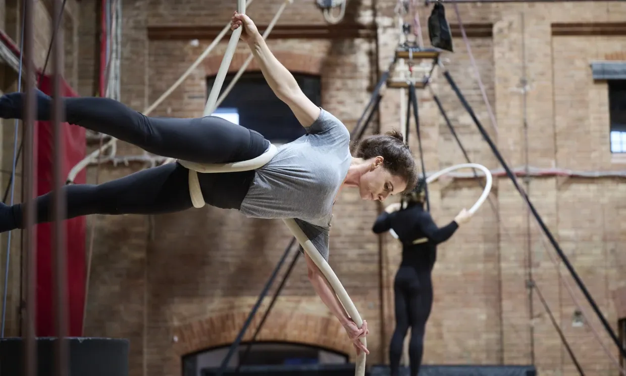 A woman hangs from aerial ropes with expert poise.